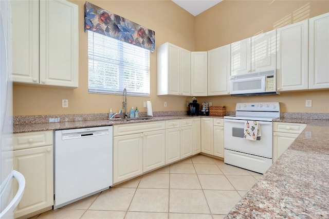 kitchen featuring white appliances, light stone counters, white cabinetry, a sink, and light tile patterned flooring