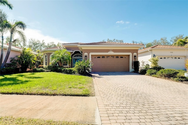 mediterranean / spanish home featuring a garage, a tiled roof, decorative driveway, and stucco siding