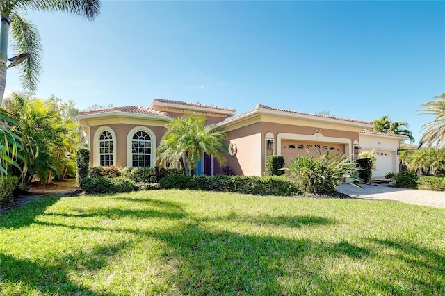 mediterranean / spanish house with driveway, a garage, stucco siding, and a front yard