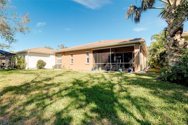 back of house with a yard, stucco siding, a sunroom, and ceiling fan