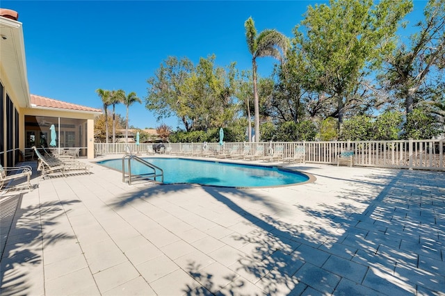 pool featuring a sunroom, a patio area, and fence