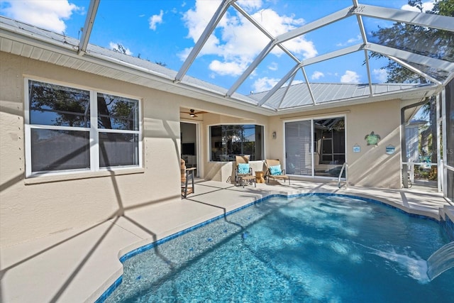 view of swimming pool with a patio, ceiling fan, and glass enclosure