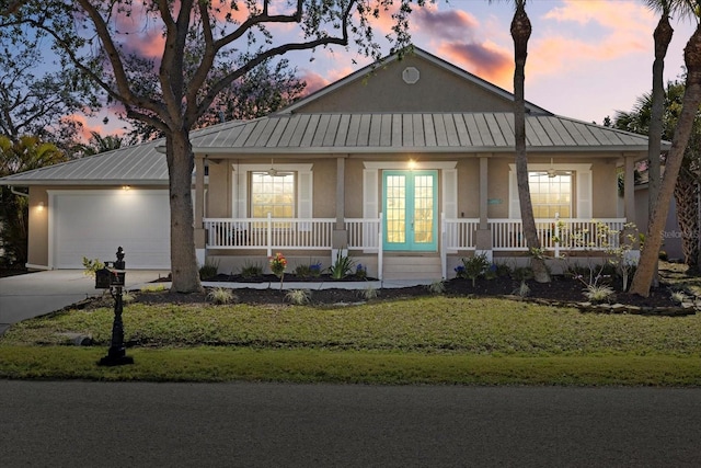 view of front of home featuring a garage, french doors, and a lawn