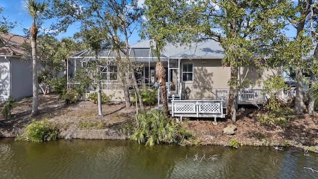 rear view of house with a deck with water view and a lanai