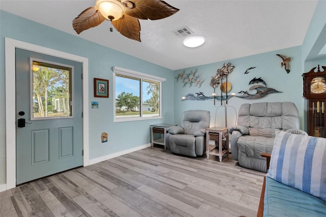 living area with a ceiling fan, light wood-type flooring, visible vents, and baseboards