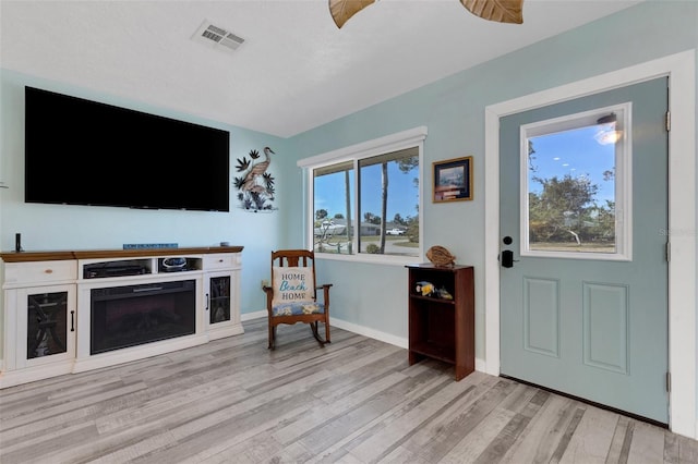 entrance foyer with light wood-style floors, baseboards, a fireplace, and visible vents