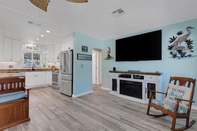 kitchen featuring visible vents, a sink, stainless steel fridge with ice dispenser, and stove