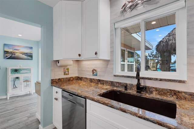 kitchen featuring dark stone counters, a sink, white cabinetry, backsplash, and dishwasher