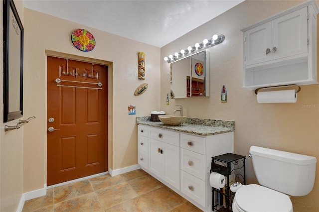 bathroom with baseboards, vanity, and toilet