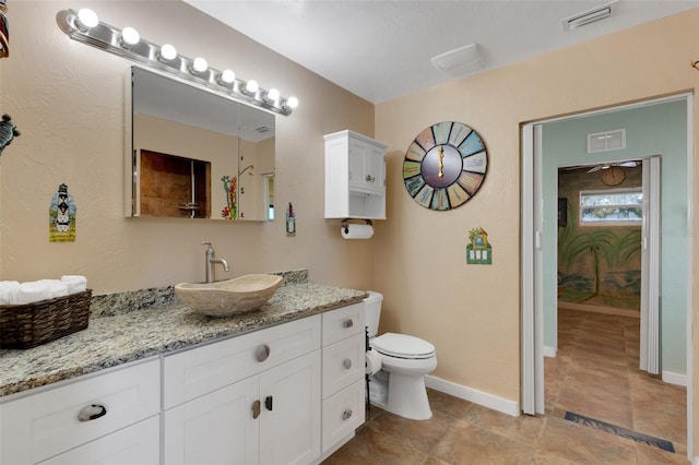 bathroom with toilet, vanity, visible vents, and baseboards