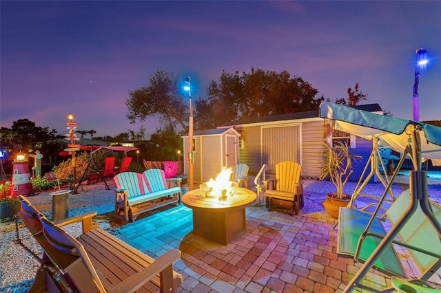 view of patio / terrace with a storage shed, a fire pit, and an outdoor structure