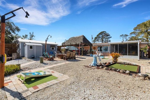 rear view of house with a patio, an outdoor fire pit, an outdoor structure, fence, and a gazebo