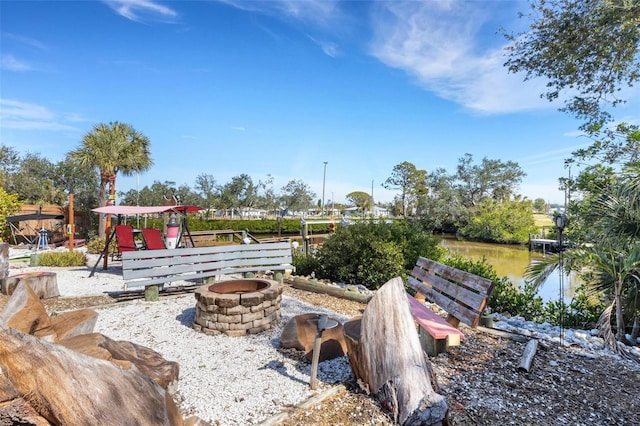 surrounding community with an outdoor fire pit and a water view