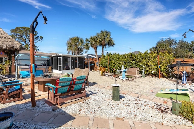 view of yard with a sunroom, a jacuzzi, a patio area, and a fire pit