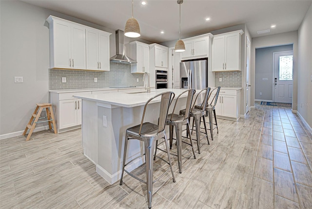 kitchen featuring stainless steel appliances, white cabinets, and wall chimney exhaust hood