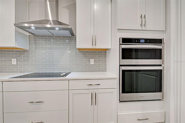 kitchen featuring double oven, white cabinets, and wall chimney exhaust hood