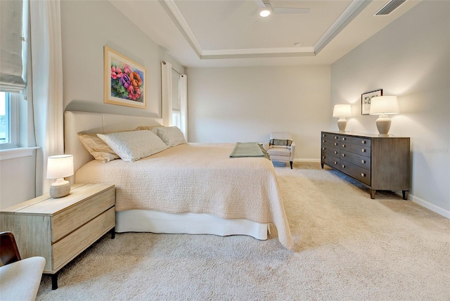 carpeted bedroom with ceiling fan and a raised ceiling