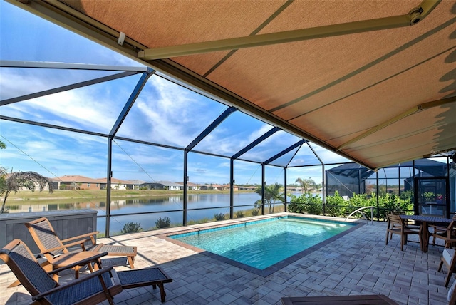 view of pool with a lanai, a patio area, a hot tub, and a water view