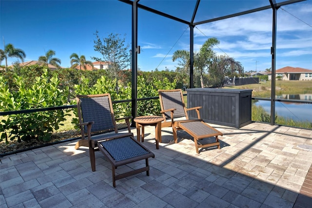 view of patio featuring a water view and glass enclosure