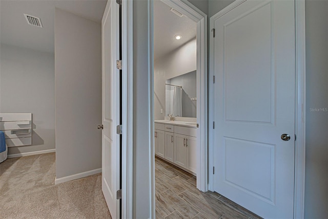 hallway with sink and light wood-type flooring