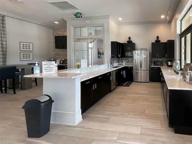 kitchen featuring sink, crown molding, backsplash, stainless steel appliances, and light stone countertops