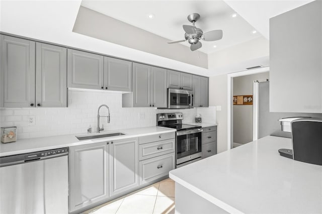 kitchen featuring light tile patterned flooring, sink, gray cabinets, stainless steel appliances, and backsplash