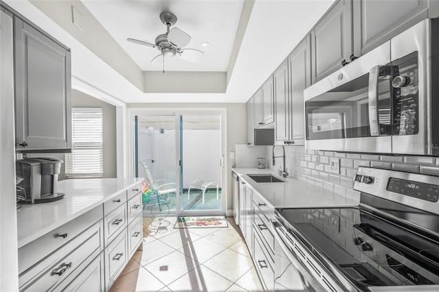 kitchen with sink, gray cabinets, ceiling fan, stainless steel appliances, and backsplash