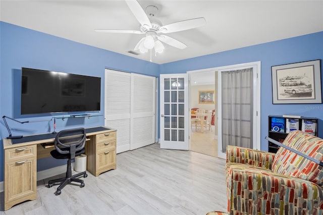 home office featuring french doors, ceiling fan, and light wood-type flooring