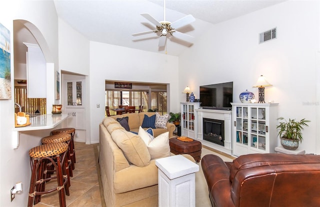 tiled living room with ceiling fan and high vaulted ceiling