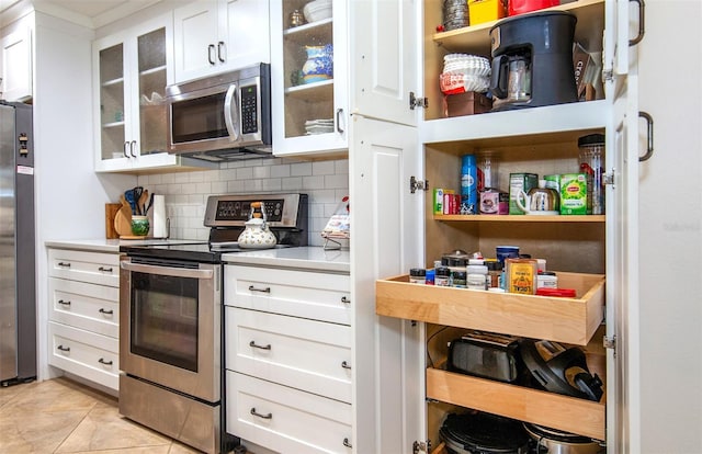 kitchen featuring light tile patterned flooring, stainless steel appliances, decorative backsplash, and white cabinets