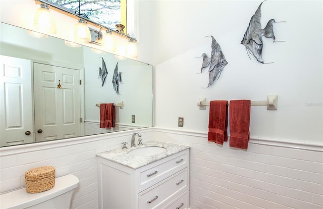 bathroom with vanity, toilet, and tile walls