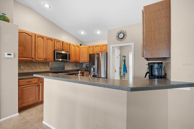 kitchen featuring lofted ceiling, light tile patterned floors, backsplash, stainless steel appliances, and kitchen peninsula