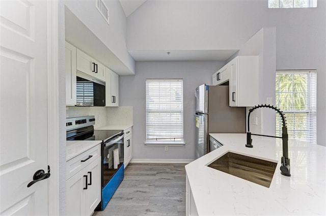 kitchen with light stone counters, appliances with stainless steel finishes, sink, and white cabinets