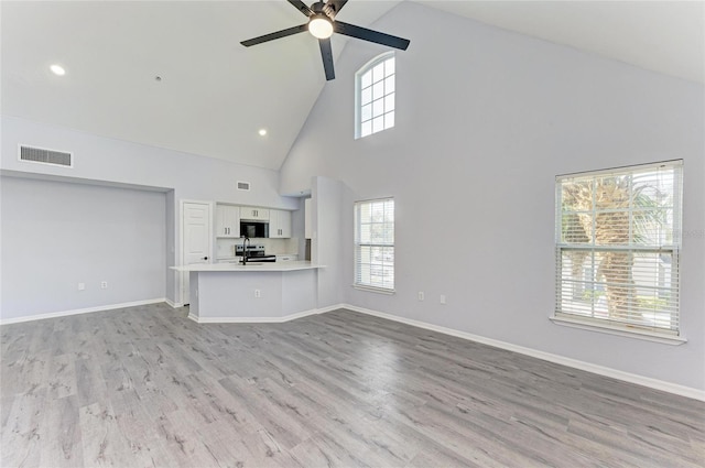 unfurnished living room featuring light hardwood / wood-style flooring, high vaulted ceiling, and ceiling fan