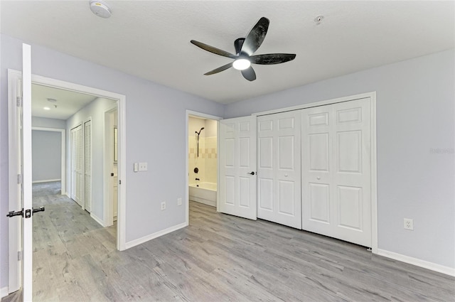 unfurnished bedroom featuring ensuite bath, a closet, ceiling fan, and light wood-type flooring