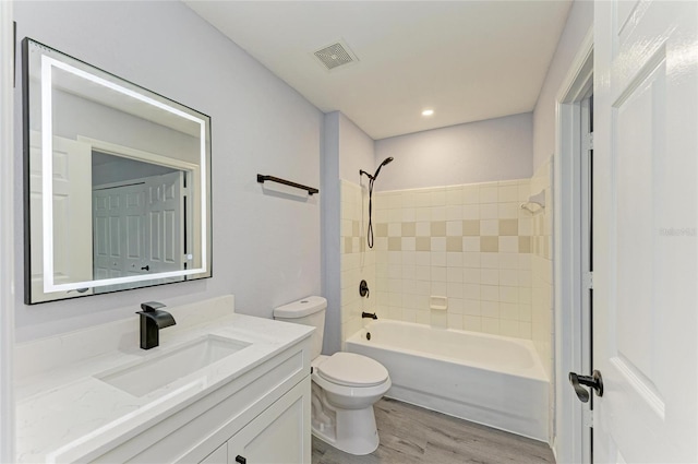 full bathroom with vanity, toilet, tiled shower / bath combo, and hardwood / wood-style floors