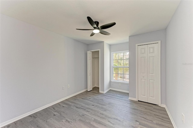 unfurnished bedroom featuring ceiling fan, light hardwood / wood-style flooring, and two closets