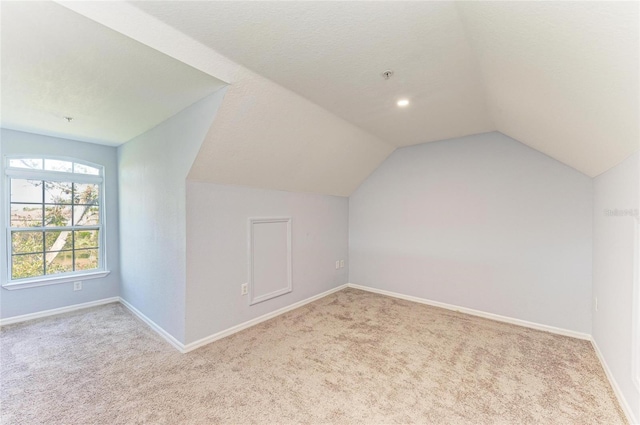 bonus room with light carpet and vaulted ceiling