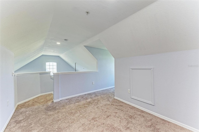 bonus room with lofted ceiling and light carpet