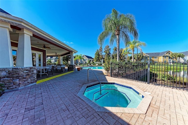 view of swimming pool featuring a community hot tub, ceiling fan, a water view, and a patio