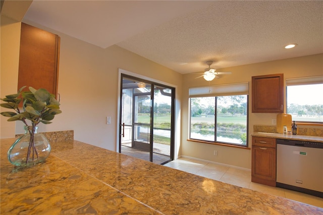 kitchen with light tile patterned flooring, stainless steel dishwasher, ceiling fan, and a textured ceiling