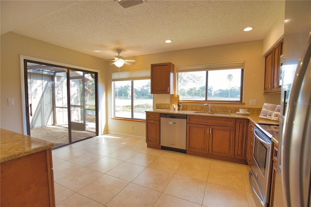 kitchen featuring stainless steel appliances, sink, a textured ceiling, and light tile patterned floors