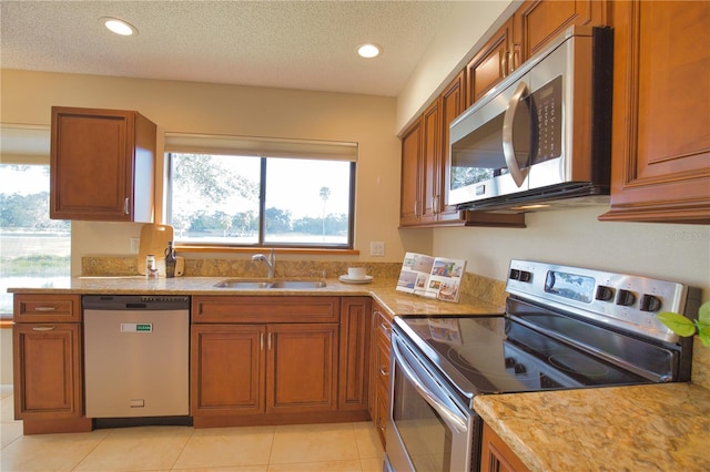 kitchen featuring stainless steel appliances, sink, a textured ceiling, and light tile patterned floors