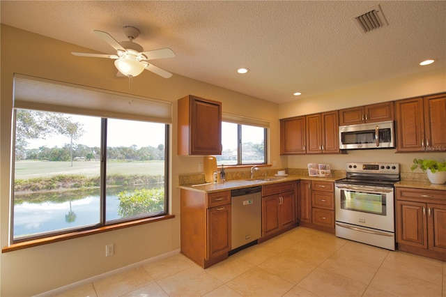 kitchen featuring stainless steel appliances, sink, light tile patterned floors, and a textured ceiling