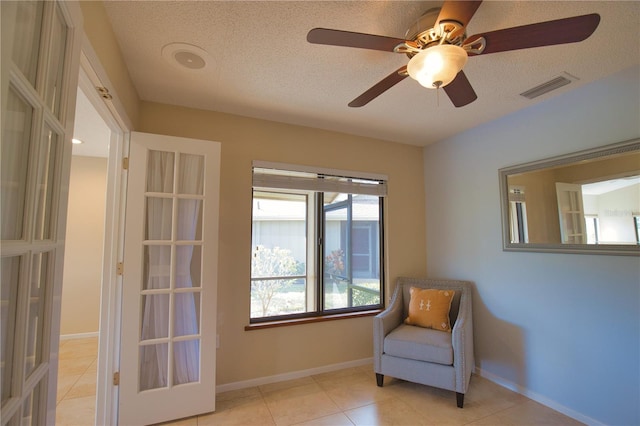 living area with french doors, ceiling fan, a textured ceiling, and light tile patterned floors