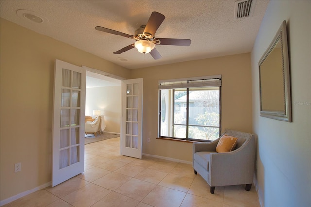 sitting room featuring ceiling fan, light tile patterned floors, a textured ceiling, and french doors