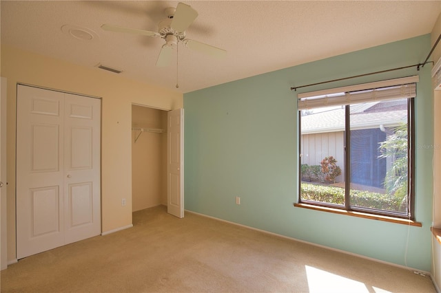 unfurnished bedroom with light colored carpet, a closet, multiple windows, and a textured ceiling