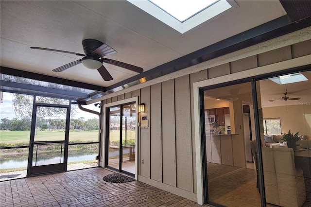 sunroom featuring a skylight, ceiling fan, and a water view