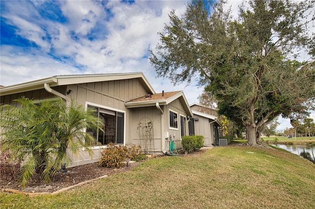 view of side of property featuring a water view, a yard, and central AC unit