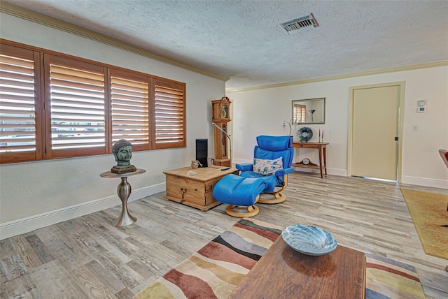 sitting room with ornamental molding, a textured ceiling, and light wood-type flooring